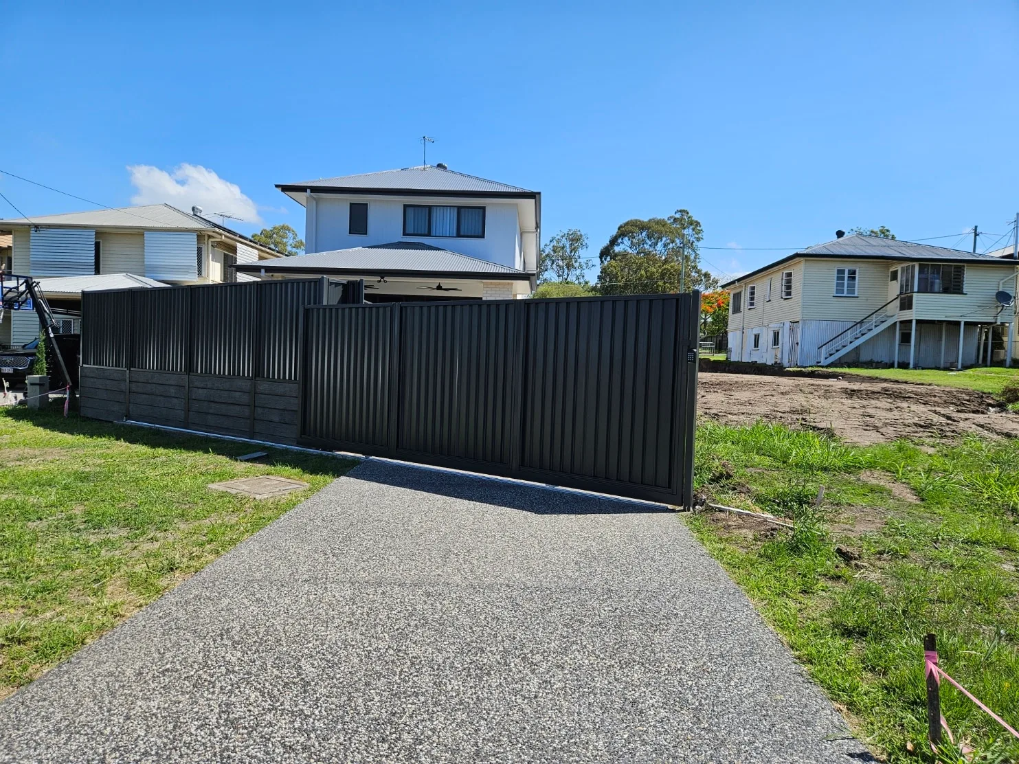 Black Colorbond-style sliding gate across an aggregate driveway