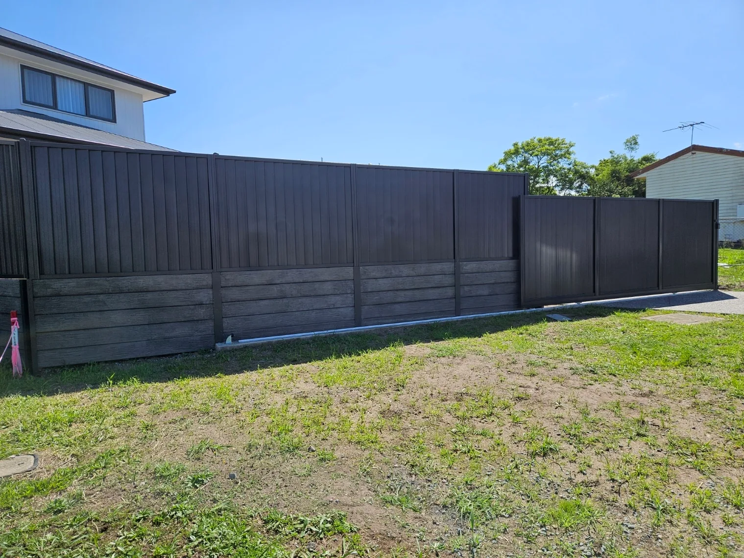 Black slat sliding gate and fence on a new residential block