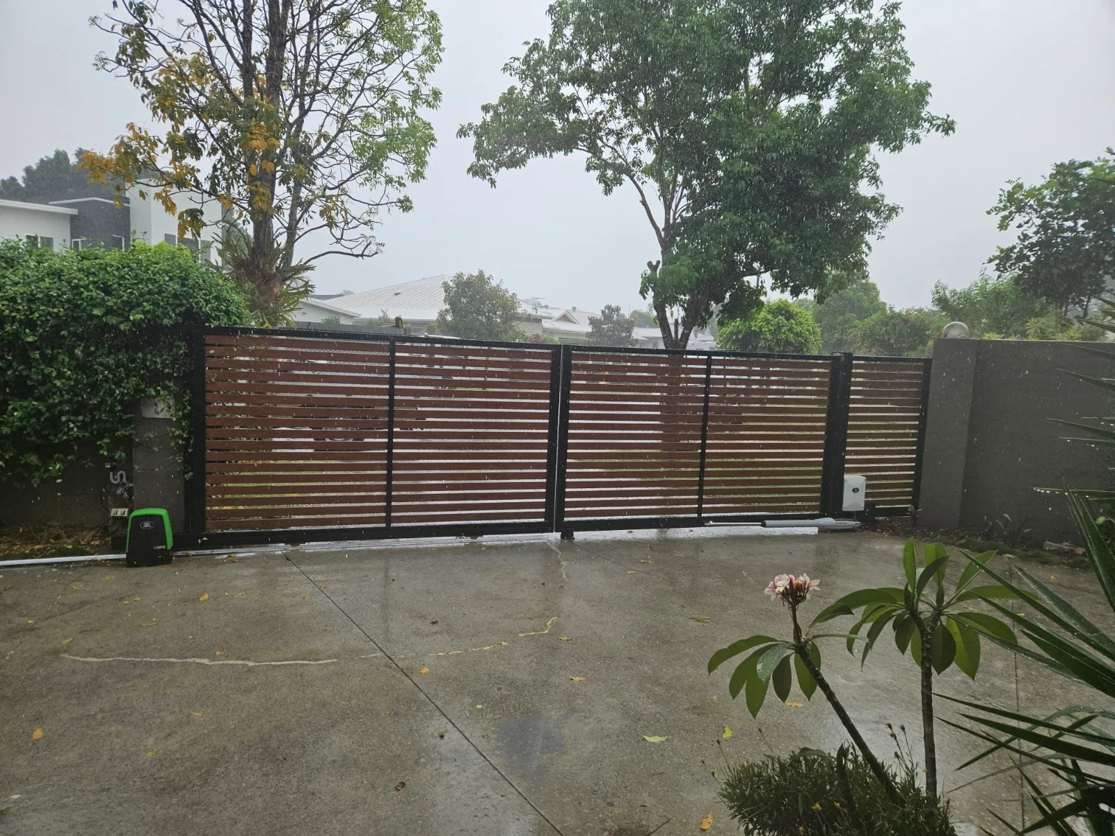 Timber-look aluminium slat sliding gate across a concrete driveway
